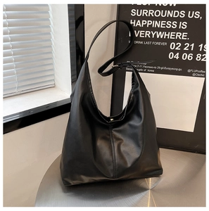 Detail of matte black leather tote bag with vertical stitching and magnetic closure
