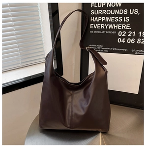 Detail view of dark brown leather tote bag with metal buckle and vertical stitching detail