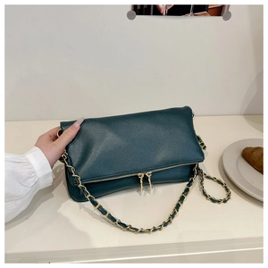 Detail of dark green litchi grain texture and gold chain on the crossbody bag