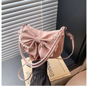 Détail d'un sac à main en satin rose avec chaîne de perles et grand nœud élégant