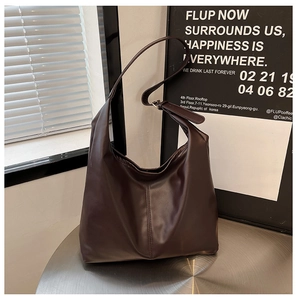 Detail of dark brown tote bag with adjustable strap on a metallic surface