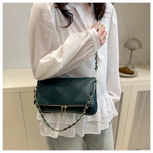 Detail of dark green lychee texture shoulder bag with gold chain and zipper tassels
