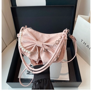 Détail du sac à nœud rose avec chaîne en perles et métal dans un coffret cadeau noir