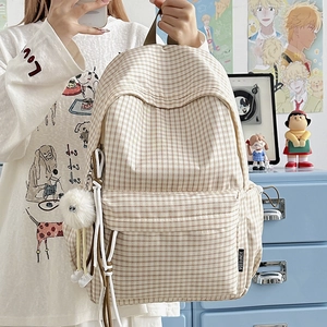 Retro plaid canvas backpack with large capacity and white pompom charm in home setting