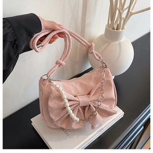 Détail du sac en satin rose avec nœud, rangée de perles et chaîne en métal argenté fleuri