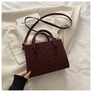 Detail view of burgundy leopard embossed suede crossbody bag with gold buckle strap