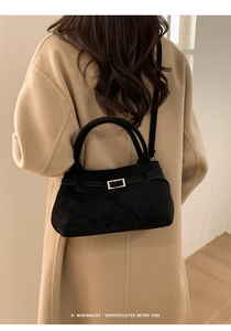Minimalist black suede tote bag with silver buckle worn over a beige cashmere coat