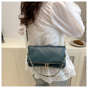 Detail of dark green litchi texture bag with metal chain strap and decorative zipper