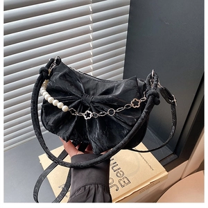 Détail du sac nœud noir avec chaîne de perles et éléments métalliques floraux