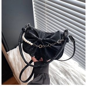 Détail du sac nœud noir avec chaîne de perles, tissu texturé et fleurs en métal doré