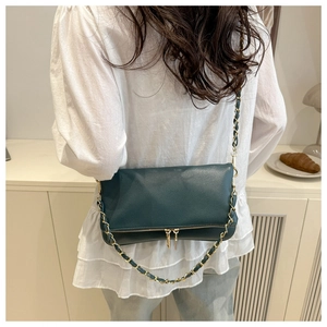 Detail of dark green lychee pattern crossbody bag with double gold zippers and chain strap
