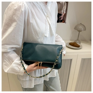 Detail of dark green lychee pattern leather shoulder bag with gold chain and dual zippers