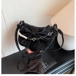 Détail du sac bandoulière noir en forme de nœud avec chaîne en perles et métal argenté