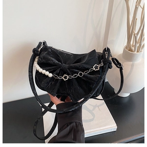 Détail du sac noir à nœud avec chaîne en perles et fleurs argentées élégantes