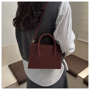 Detail view of burgundy leopard embossed suede satchel with golden hardware and straps