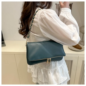Close-up of dark green lychee pattern leather shoulder bag with golden chain strap