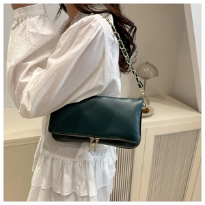 Detail of green lychee pattern shoulder bag with gold chain strap on female model