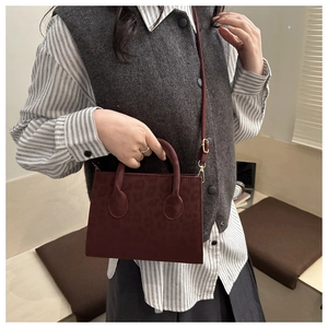 Deep red crossbody bag with leopard embossing shown on a model for autumn fashion