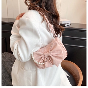 Détail du sac à bandoulière rose en forme de nœud avec chaîne en perles et cœurs