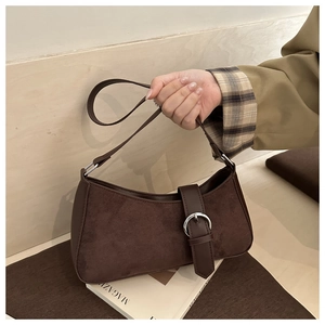 Detail of dark brown suede crescent shoulder bag with silver buckles and smooth texture