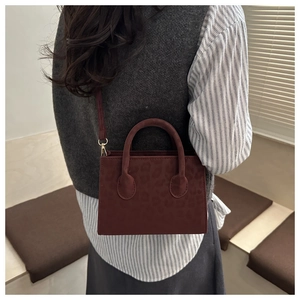 Deep red leopard print mini handbag styled on model with sleek shoulder strap detail