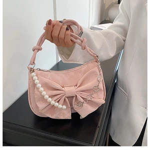 Détail du sac en satin rose avec un grand nœud et une bandoulière perle et fleur