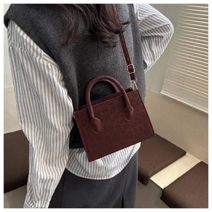 Detail of burgundy leopard embossed handbag with gold hardware and top handles