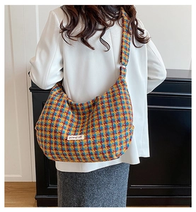 Detail of colorful plaid tweed hobo bag with power off label worn by a model