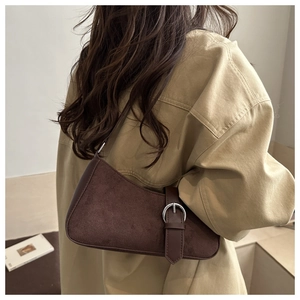 Chic dark brown suede baguette bag worn as a shoulder bag in a minimalist setting