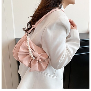 Détail d'un sac à main rose en forme de noeud avec perles et texture cuir froncé élégant