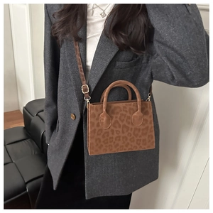 Detail of leopard print crossbody bag with gold hardware on grey suit jacket