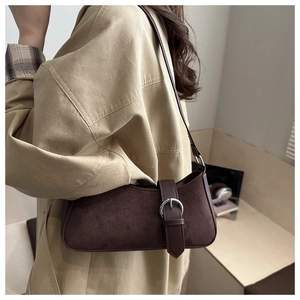 Detail of dark brown suede crescent bag with silver buckle and leather strap on model