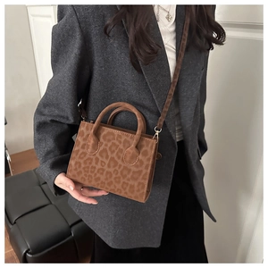 Detail of trendy leopard print handbag with top handle and gold hardware on model