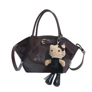 Chic dark brown glossy patent leather handbag with a plush charm on white background