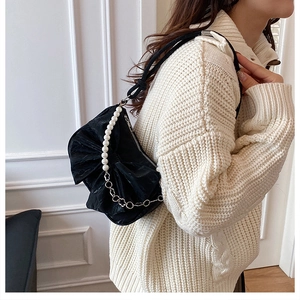 Détail d'un sac à nœud plissé noir avec bandoulière en perles et chaîne en argent