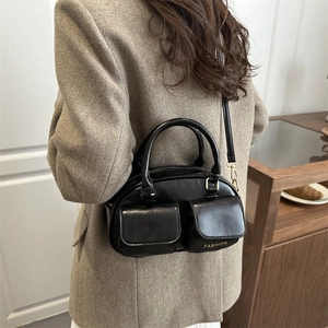 Chic black shiny leather bowling bag with dual front pockets and thin shoulder strap