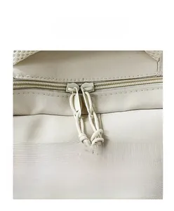 Close-up of durable dual zippers with woven pull cords on a beige nylon backpack