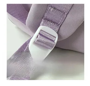 Macro detail of purple woven shoulder strap with white adjustable plastic buckle for backpack