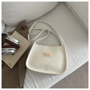 Detail of cream white leather shoulder bag with gold logo on a cozy minimalist background
