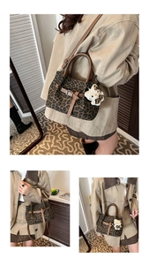Detail der Handtasche mit Leopardenmuster, braunem Lederbesatz und Katzenanhänger