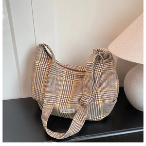 Close-up of retro plaid dumpling bag showing adjustable wide shoulder strap and woven texture
