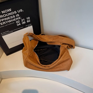 Brown suede hobo tote bag with spacious interior and zipper closure on a white surface