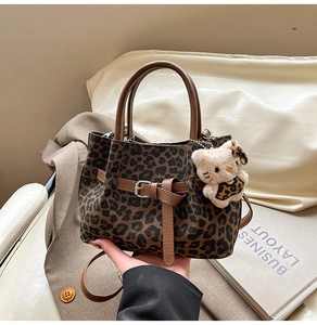 Detail der Handtasche mit Leopardenmuster, Ledergriffen und Plüschkatzen-Anhänger