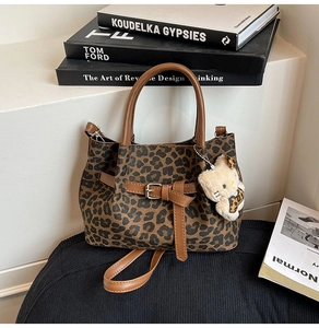 Detail der Handtasche mit Leopardenmuster, braunem Ledergriff und Katzen-Plüschanhänger