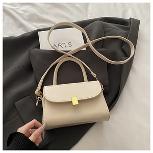 Detail of a creamy vintage square shoulder bag with a gold buckle on grey blazer
