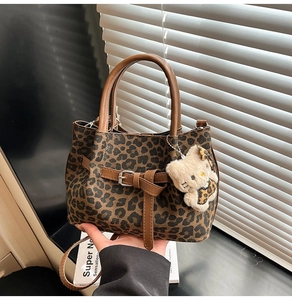 Detail der Handtasche mit Leopardenmuster, braunen Griffen und Katzenanhänger