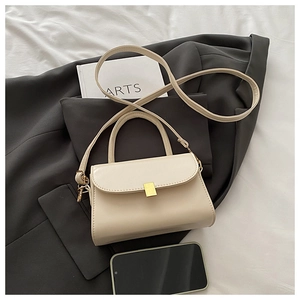 Detail of cream crossbody bag showing fine PU leather texture and gold metal buckle