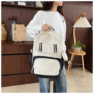 Close-up of black and white multi-pocket backpack with striped straps and side pouch