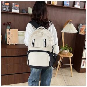 Close-up of a two-tone cream and black school backpack with a side round pouch detail