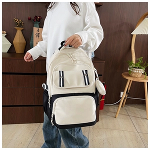 Close-up of black and white canvas backpack with multiple pockets and small round pouch